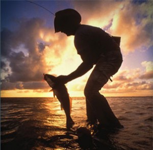 A fisherman takes a fish off the line in Galveston Bay.